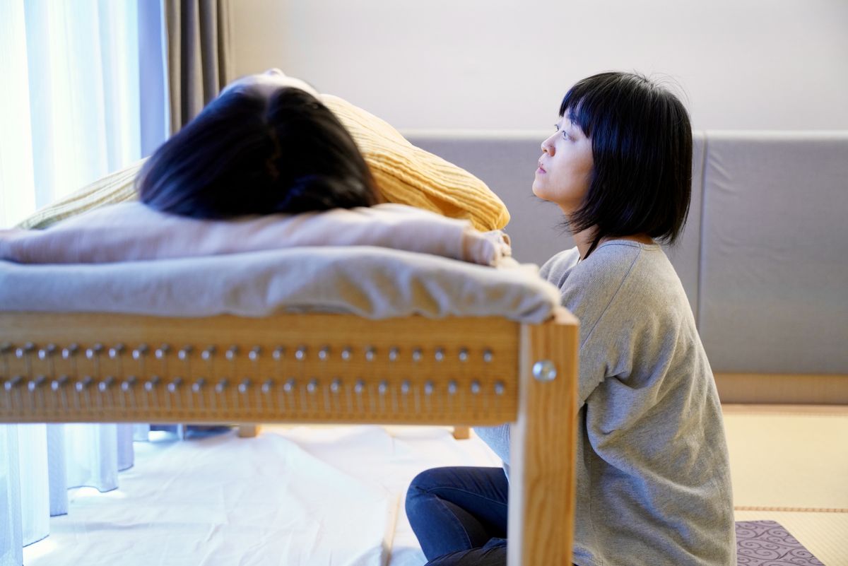 琴師在琴床旁陪伴躺著休息的個案